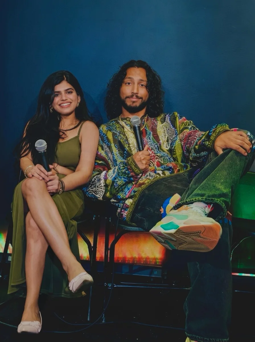 Surbhi and Wyatt sitting together on stage at Top Secret Comedy Club